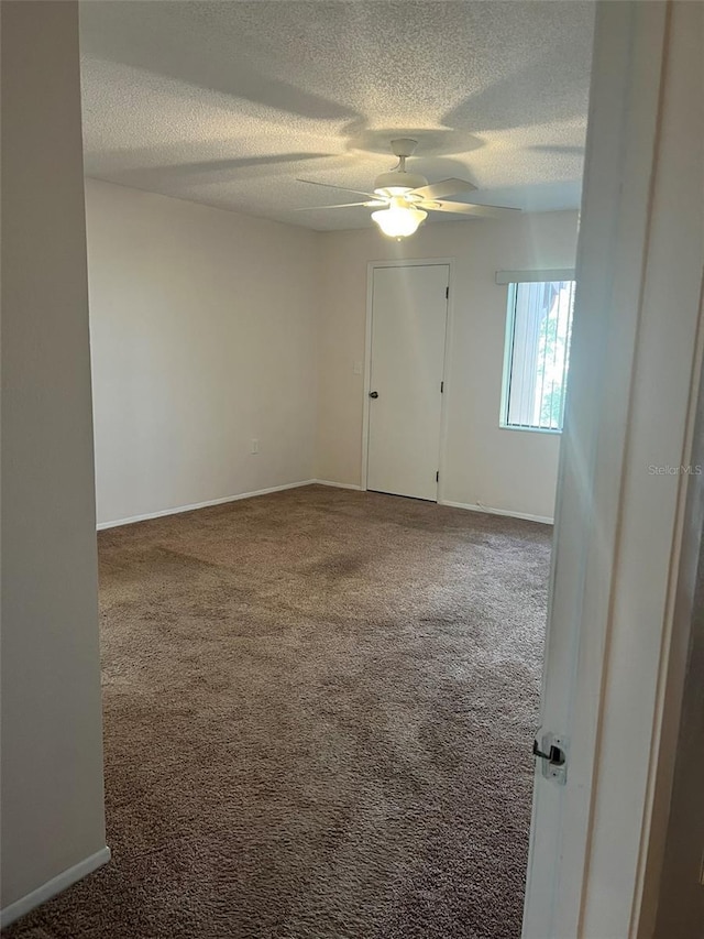 unfurnished room with ceiling fan, carpet flooring, and a textured ceiling