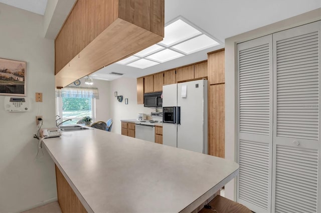 kitchen featuring a kitchen breakfast bar, sink, white appliances, and kitchen peninsula