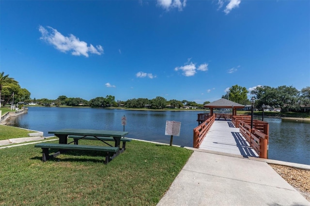 view of dock with a gazebo, a water view, and a lawn