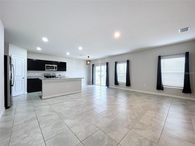 kitchen featuring a notable chandelier, stainless steel appliances, an island with sink, and light tile patterned floors