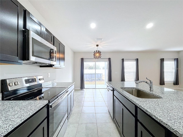 kitchen featuring light tile patterned flooring, sink, appliances with stainless steel finishes, pendant lighting, and light stone countertops