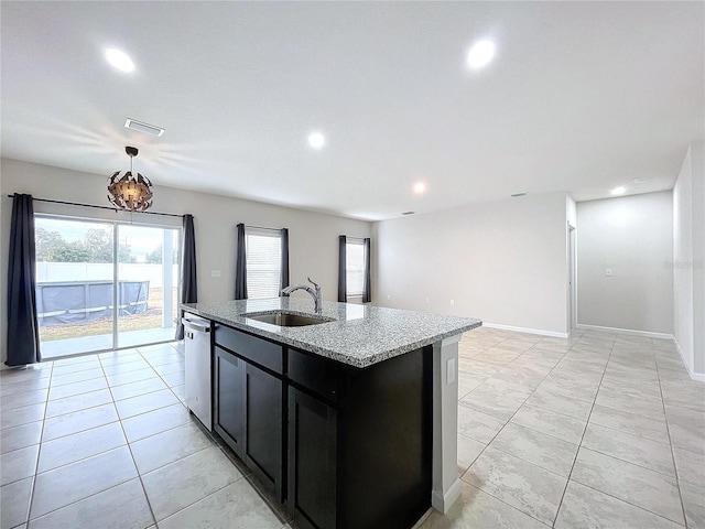 kitchen with pendant lighting, sink, light stone counters, a center island with sink, and stainless steel dishwasher