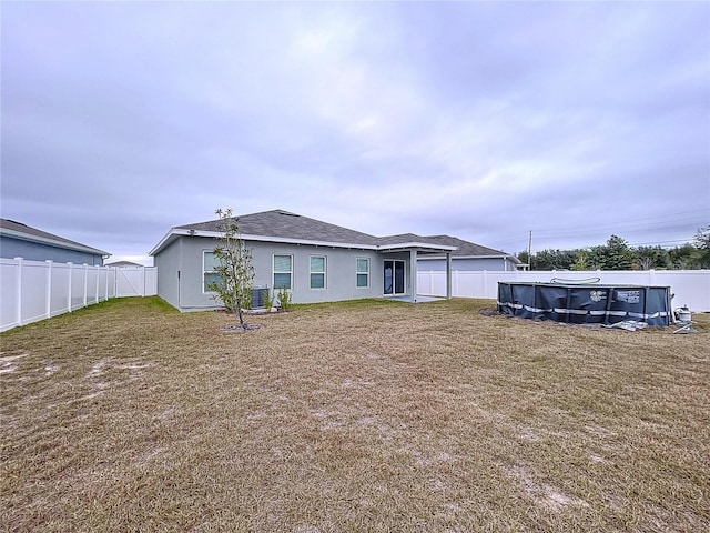 back of house with a covered pool and a lawn