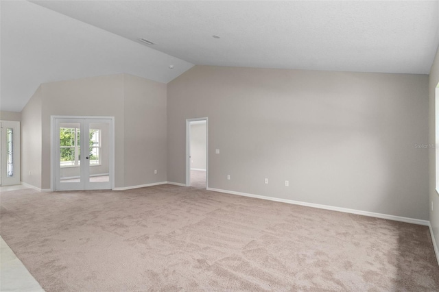 carpeted spare room with lofted ceiling and french doors