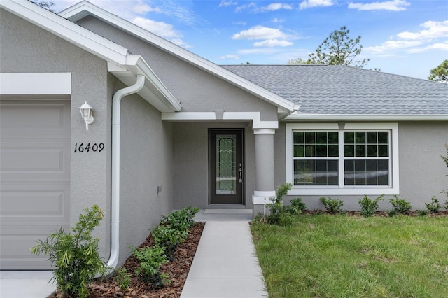 view of exterior entry featuring a garage and a yard