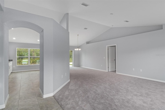 spare room with vaulted ceiling, light colored carpet, and a notable chandelier