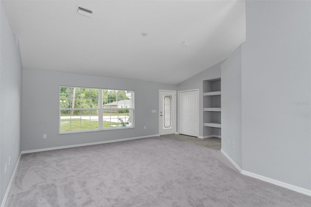 unfurnished living room with light colored carpet, vaulted ceiling, and built in features