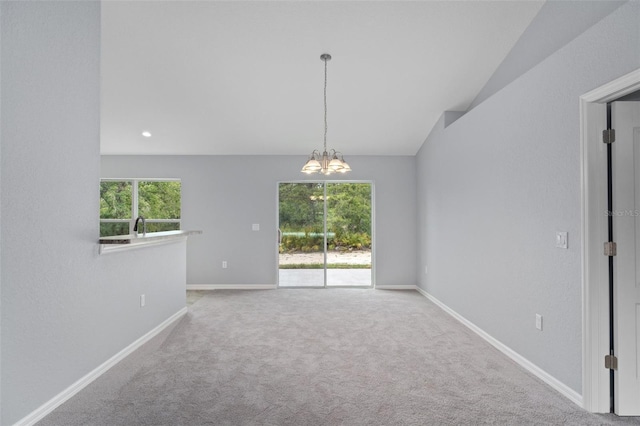 carpeted empty room featuring vaulted ceiling, plenty of natural light, sink, and a chandelier