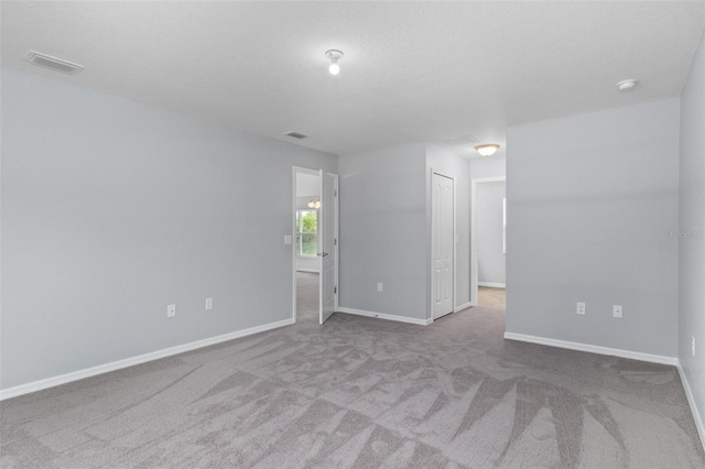 unfurnished room with carpet and a textured ceiling