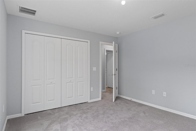 unfurnished bedroom with light colored carpet and a closet