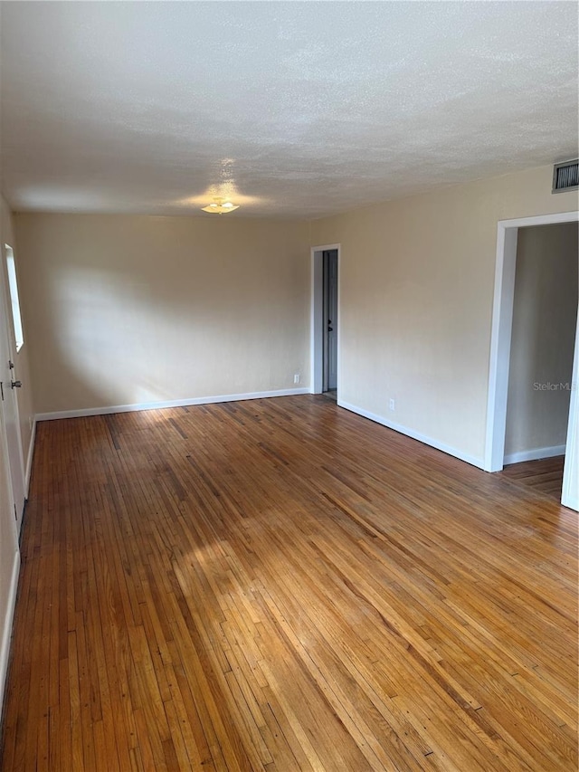 unfurnished room with wood-type flooring and a textured ceiling