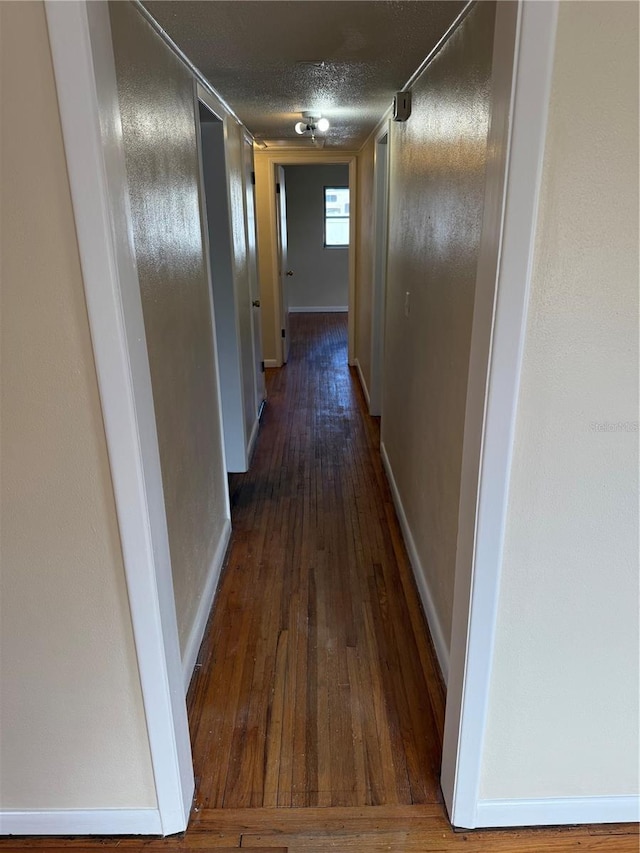 corridor with dark wood-type flooring and a textured ceiling