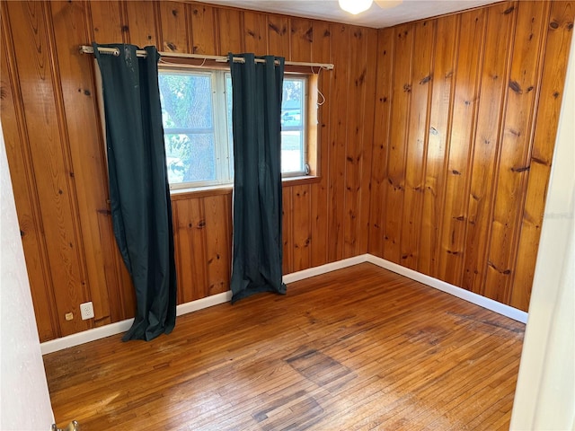 empty room with hardwood / wood-style floors and wood walls