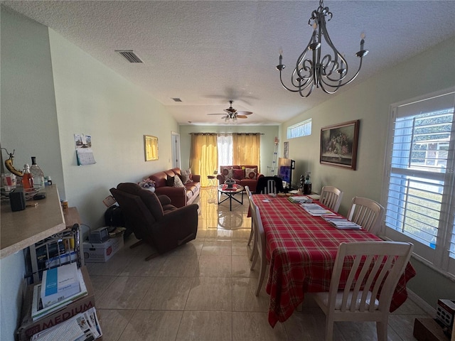 tiled dining area with a textured ceiling, ceiling fan with notable chandelier, and a healthy amount of sunlight