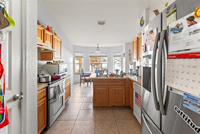 kitchen featuring sink, decorative light fixtures, light tile patterned floors, appliances with stainless steel finishes, and kitchen peninsula