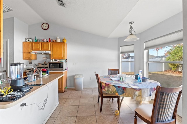 kitchen featuring sink, vaulted ceiling, hanging light fixtures, and light tile patterned floors