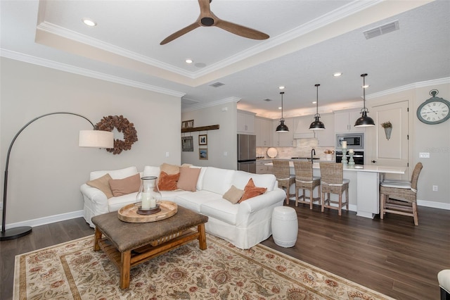 living room with a raised ceiling, crown molding, and dark hardwood / wood-style floors