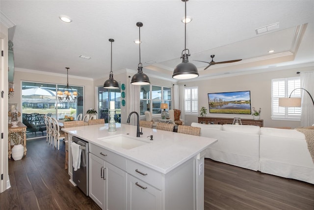 kitchen featuring pendant lighting, white cabinetry, an island with sink, sink, and stainless steel dishwasher