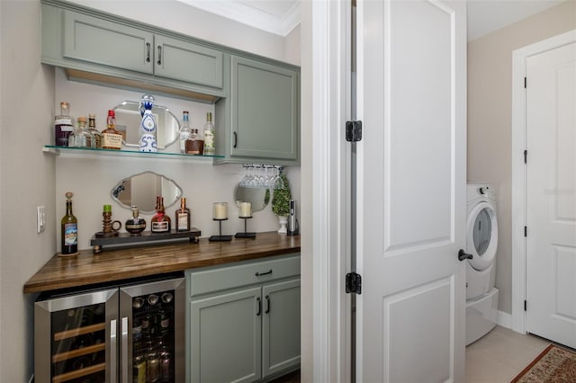 bar with washer / dryer, butcher block counters, green cabinetry, light tile patterned floors, and beverage cooler