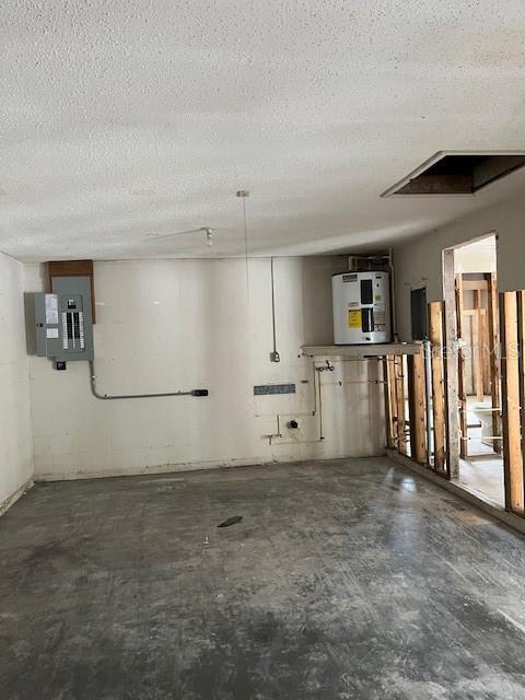 basement featuring water heater, electric panel, and a textured ceiling