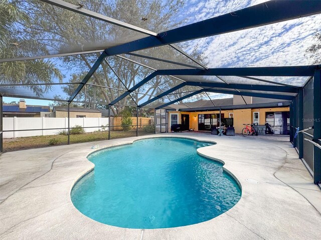 view of pool featuring glass enclosure, a patio area, a fenced backyard, and a fenced in pool