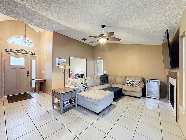 living area featuring visible vents, lofted ceiling, light tile patterned floors, ceiling fan with notable chandelier, and a textured ceiling