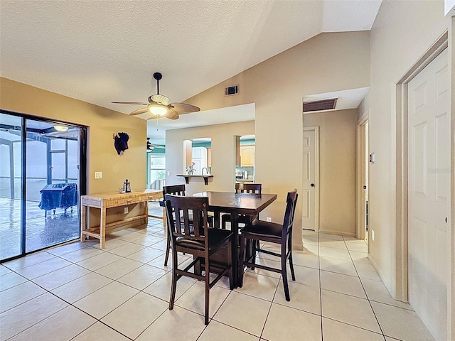 dining room featuring ceiling fan, lofted ceiling, a textured ceiling, and light tile patterned flooring