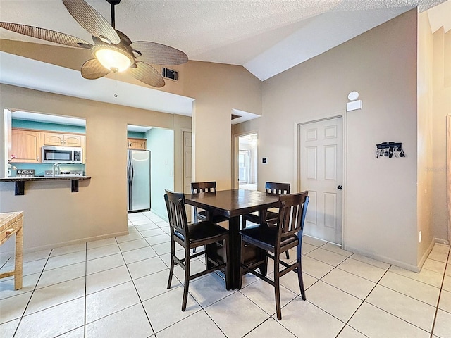 dining area with visible vents, ceiling fan, vaulted ceiling, light tile patterned floors, and a textured ceiling