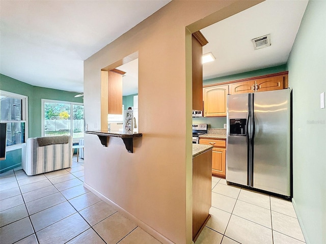 kitchen with visible vents, a breakfast bar, a ceiling fan, stainless steel appliances, and light tile patterned flooring