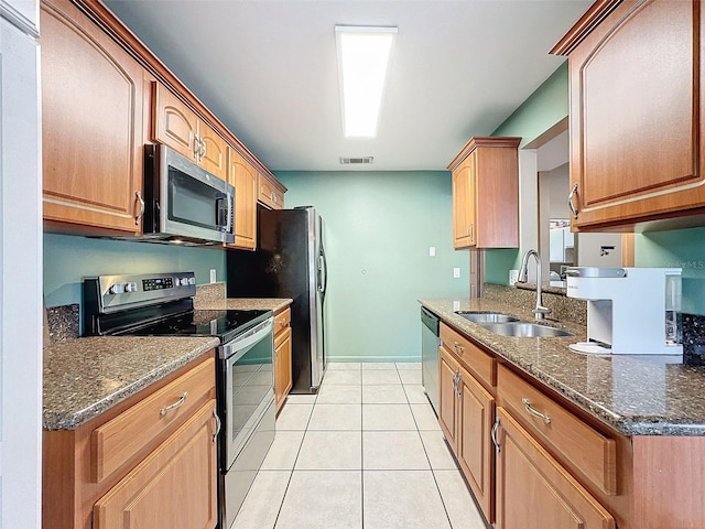 kitchen with visible vents, light tile patterned floors, dark stone countertops, appliances with stainless steel finishes, and a sink