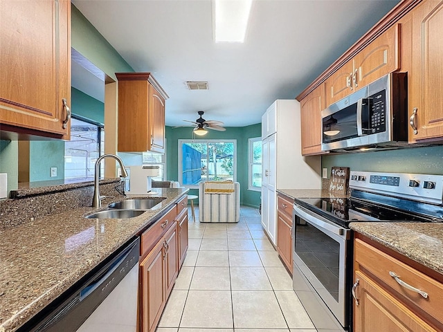 kitchen featuring visible vents, dark stone counters, light tile patterned floors, appliances with stainless steel finishes, and a sink