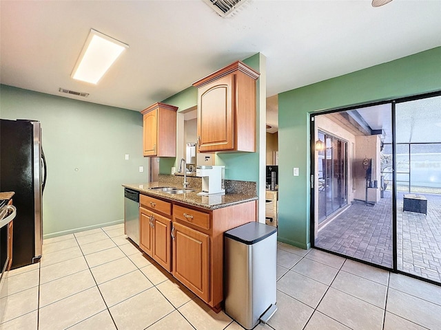 kitchen with a sink, visible vents, dark stone countertops, and stainless steel appliances