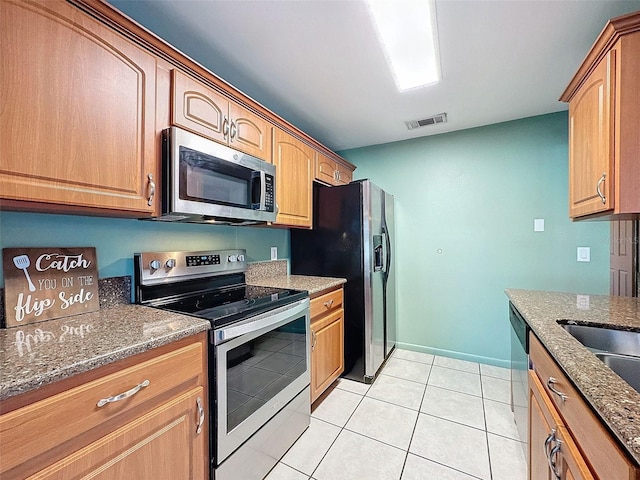 kitchen with light tile patterned floors, baseboards, visible vents, stone countertops, and appliances with stainless steel finishes