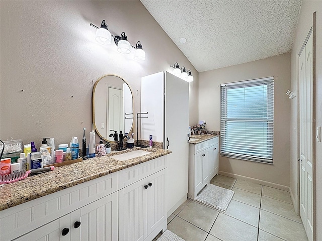 bathroom featuring vanity, baseboards, tile patterned flooring, vaulted ceiling, and a textured ceiling