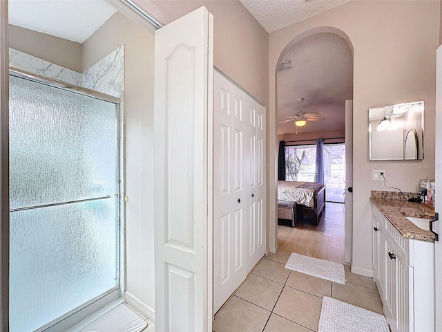 ensuite bathroom with tile patterned flooring, a stall shower, ensuite bath, a textured ceiling, and vanity