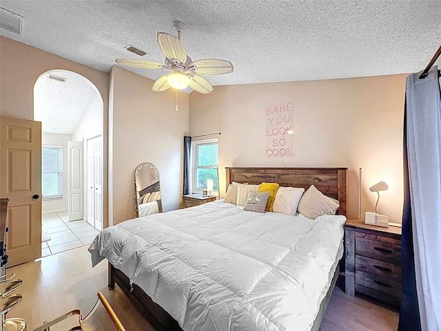 bedroom featuring visible vents, a textured ceiling, and vaulted ceiling