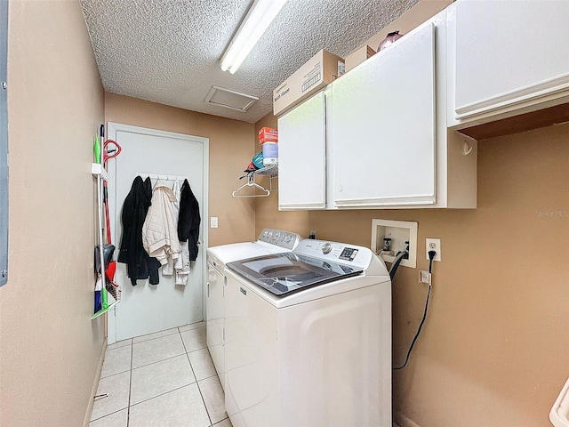 laundry area featuring light tile patterned floors, washing machine and clothes dryer, attic access, cabinet space, and a textured ceiling