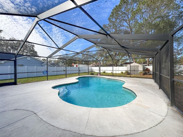 view of pool featuring a patio, a fenced backyard, glass enclosure, a storage shed, and an outdoor structure