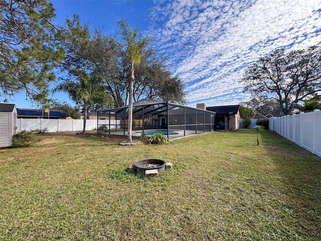 view of yard featuring a fenced backyard, a shed, an outdoor structure, a fenced in pool, and a lanai