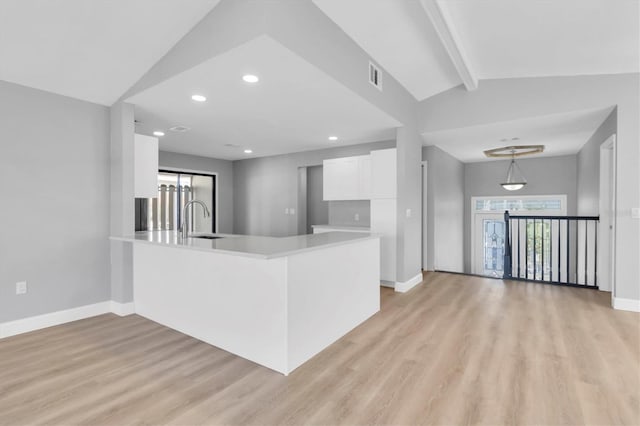 5925 Seaside Dr, New Port Richey, FL 34652 - kitchen with light hardwood / wood-style flooring, hanging light fixtures, vaulted ceiling with beams, white cabinets, and kitchen peninsula