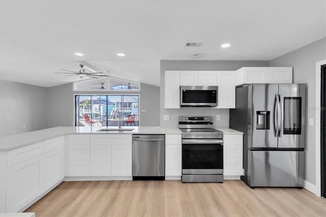 5925 Seaside Dr, New Port Richey, FL 34652 - kitchen with lofted ceiling, sink, white cabinetry, stainless steel appliances, and kitchen peninsula
