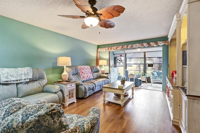 living room featuring ceiling fan, a textured ceiling, and light hardwood / wood-style floors