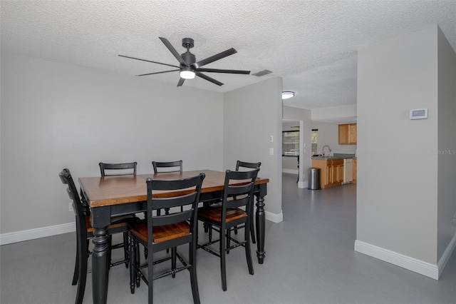 dining room featuring ceiling fan, sink, and a textured ceiling