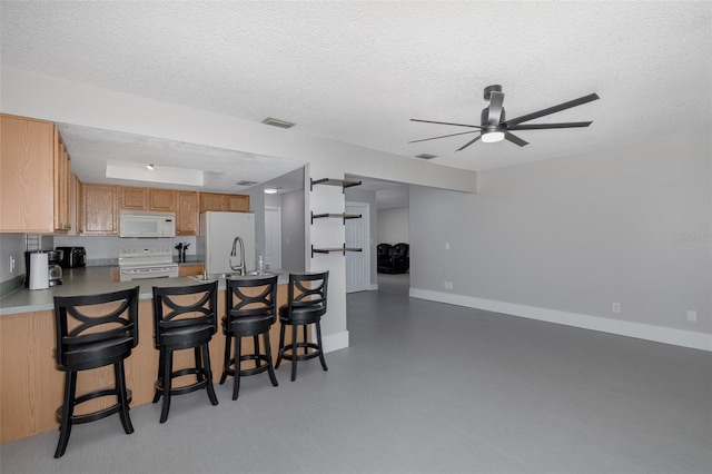 kitchen featuring white appliances, a textured ceiling, a kitchen breakfast bar, kitchen peninsula, and ceiling fan