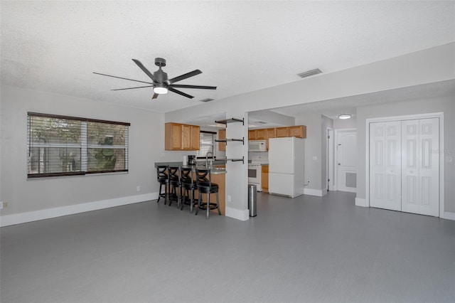 living room with ceiling fan, sink, and a textured ceiling