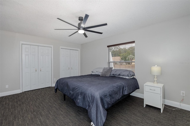 bedroom featuring ceiling fan, dark carpet, a textured ceiling, and two closets