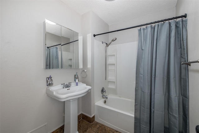 bathroom with shower / bathtub combination with curtain and a textured ceiling