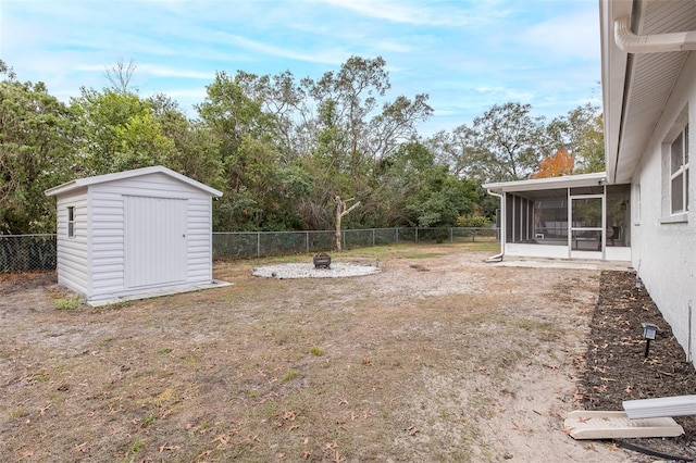 view of yard featuring a storage shed, a sunroom, and an outdoor fire pit