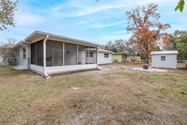 back of property with a lawn, a sunroom, and a storage unit