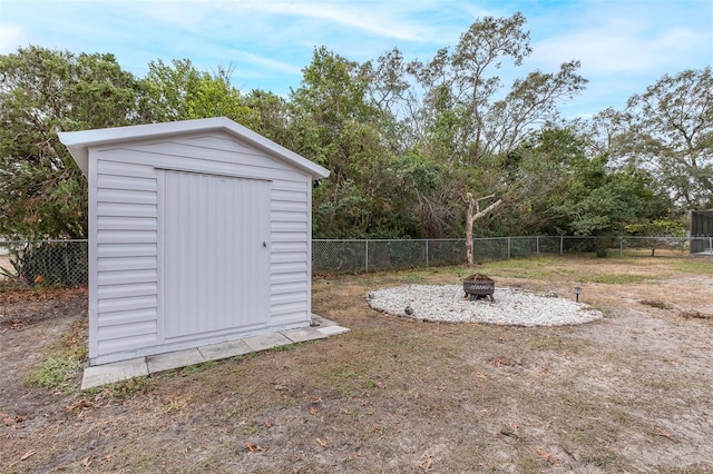 view of yard featuring a storage shed and an outdoor fire pit